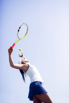 Beautiful female tennis player serving