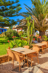 Fototapeta na wymiar Tables with chairs in green park area of Luz town, seaside resort in coast of Algarve region, Portugal