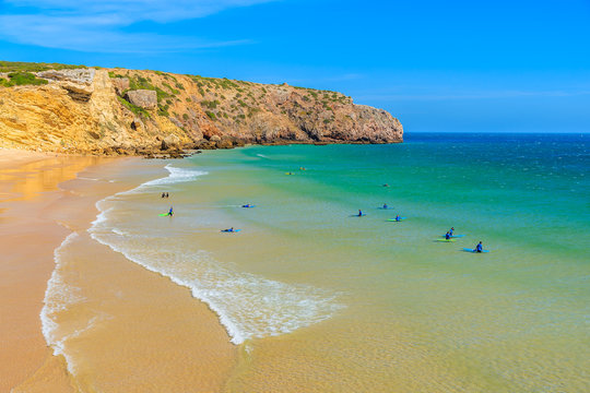 Surfers on Praia do Zavial beach with turquoise sea water, Algarve region, Portugal