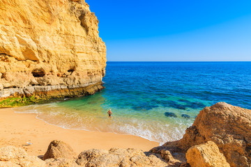 Unidentified man standing in water on beautiful Val Centianes beach, Algarve region, Portugal