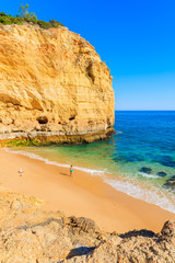 Fototapeta premium Unidentified woman walking on sandy beautiful Val Centianes beach, Algarve region, Portugal