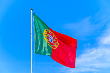 Portuguese flag waving in the wind against a blue sky background at Silves castle, Portuga