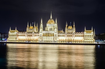 Night view over building of hungarian parliament in budapest taken from opposite shore of danube...