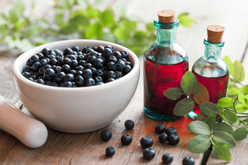Mortar with blueberries and small bottles of tincture or cosmeti