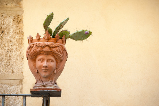 Terracotta vase with a cactus plant set in the corner of a balcony along the streets of Caltagirone, Sicily