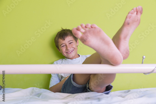 Little Kid Smiling With Dirty Feet And Sitting At Bed Little Kid Smiling With Dirty Feet And Sitting At Bed
