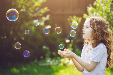 little girl catches soap bubbles