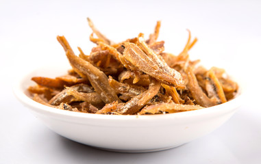 Deep fried anchovies in white bowl over white background