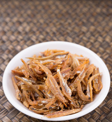 Deep fried anchovies in white bowl over rustic wiccker background