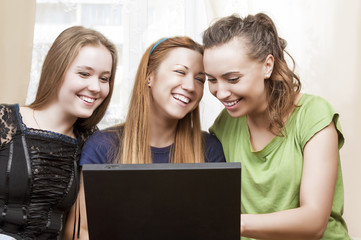 Friendship Concepts: Three Laughing Caucasian Girls Using Laptop