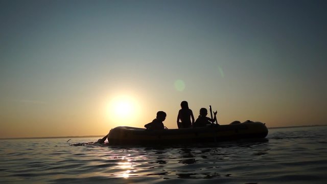 Children playing with rubber boat with sunset in background