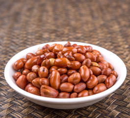Deep fried peanuts in white bowl over rustic wicker background
