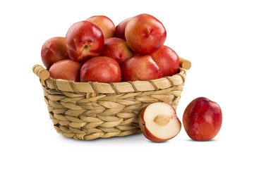 Some peaches in a basket over a wooden surface on a green and na