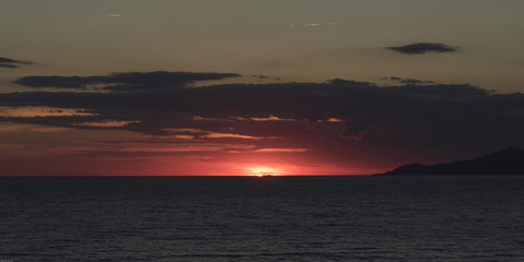 Sunset in the Gulf of Palinuro. Summer evening, fire red clouds, the sun dips to the horizon, to...