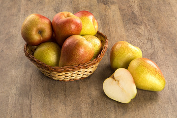 Some pears in a basket over a wooden surface seen from above