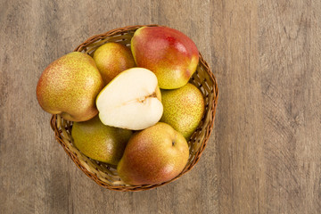 Some pears in a basket over a wooden surface seen from above