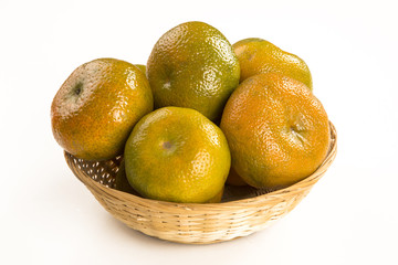 Some tangerines in a basket over a wooden surface