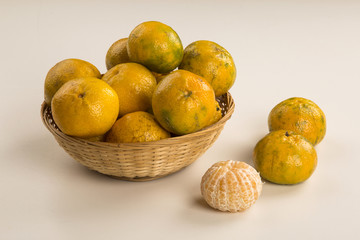 Some tangerines in a basket over a wooden surface