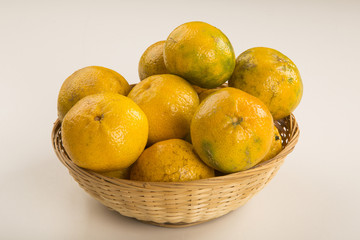 Some tangerines in a basket over a wooden surface