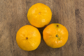 Some tangerines in a basket over a wooden surface