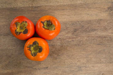 Some khaki fruits over a wooden surface