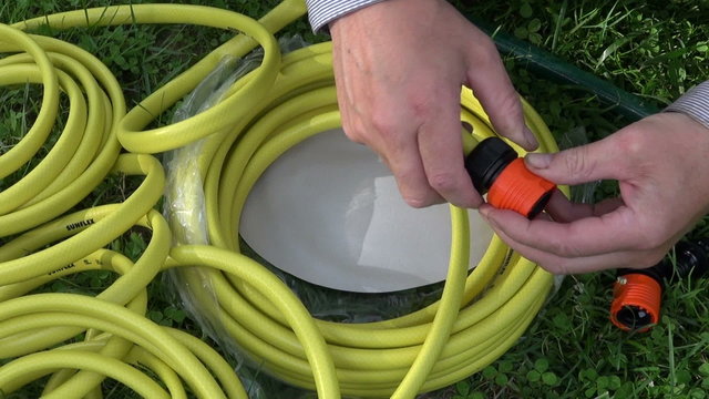 two hands preparing water hose junction on the grass