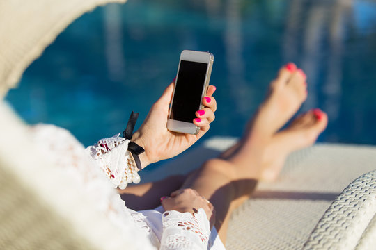 Woman holding smartphone by the pool