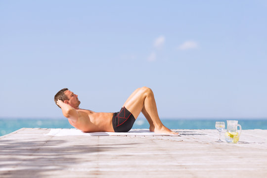 Young fit man doing abs crunches exercise outdoors
