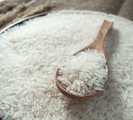 White rice in the wooden spoon and on rice background