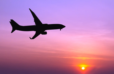 Fototapeta na wymiar Silhouetted commercial airplane flying at sunset