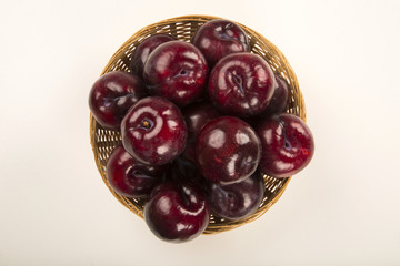 Fresh bright plums in the bowl on board