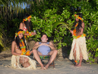 Man in retro swimsuit is surrounded by hula hawaii dancers