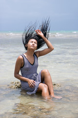 Naklejka premium woman sitting in the sea and playful with her hair 