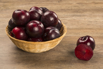 Fresh bright plums in the bowl on board