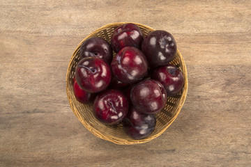 Fresh bright plums in the bowl on board