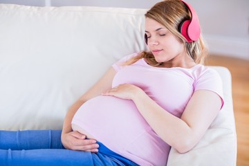 Obraz na płótnie Canvas Pregnant woman listening music and touching her belly