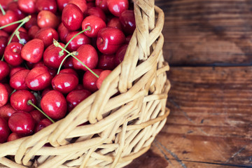 Ripe organic homegrown cherries in a basket, on wooden background
