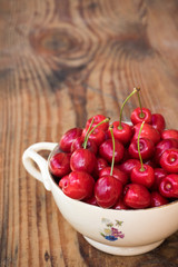 Ripe organic homegrown cherries in a vintage ceramic bowl, on wooden background