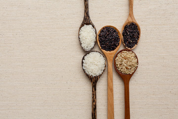 Wooden spoon collection and raw rice with space on background