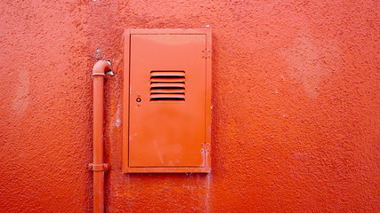 metal pipe and electric box on orange color wall