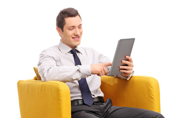 Businessman working on tablet seated in an armchair