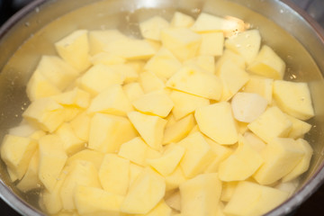 Closeup of potatoes cut in pieces in water with selective focus