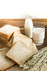 glass of milk and whole wheat bread on the wooden board