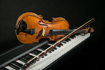 Fototapeta premium Piano keyboards with old violin on dark background.