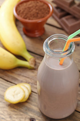 bottiglia latte cioccolato e banane sfondo rustico