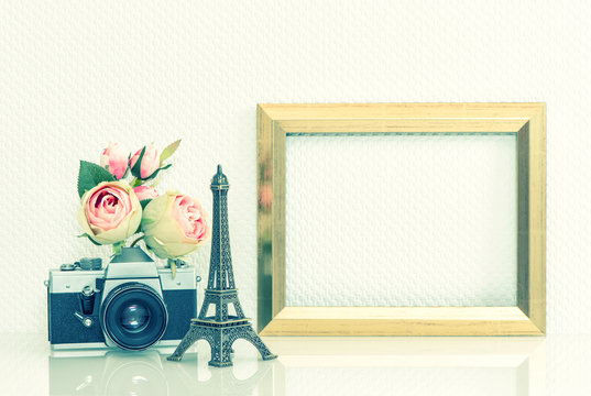 Golden picture frame, rose flowers and vintage camera. Eiffel To