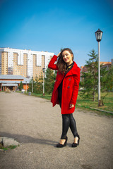 Beautiful girl in a red coat on a park alley