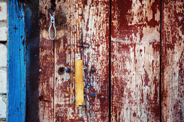 A wooden vintage scaled red door with handle and blue aperture 