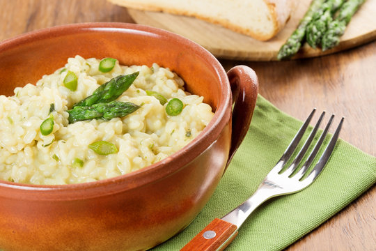 risotto with asparagus in a terracotta bowl over a green napkin