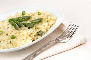 plate of risotto with asparagus over a napkin and fork